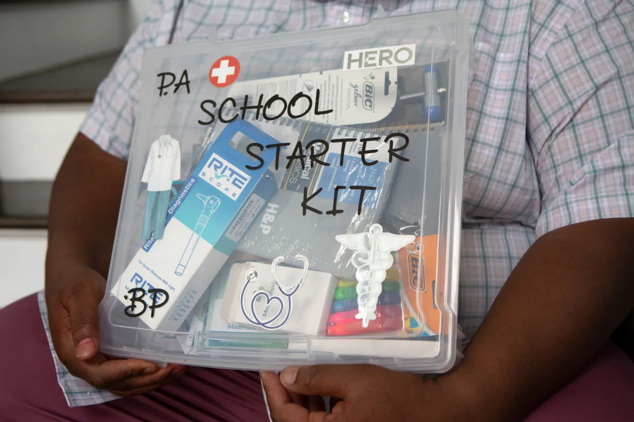 Benjamin Pinckney holds a clear crate labeled "PA School Starter Kit."