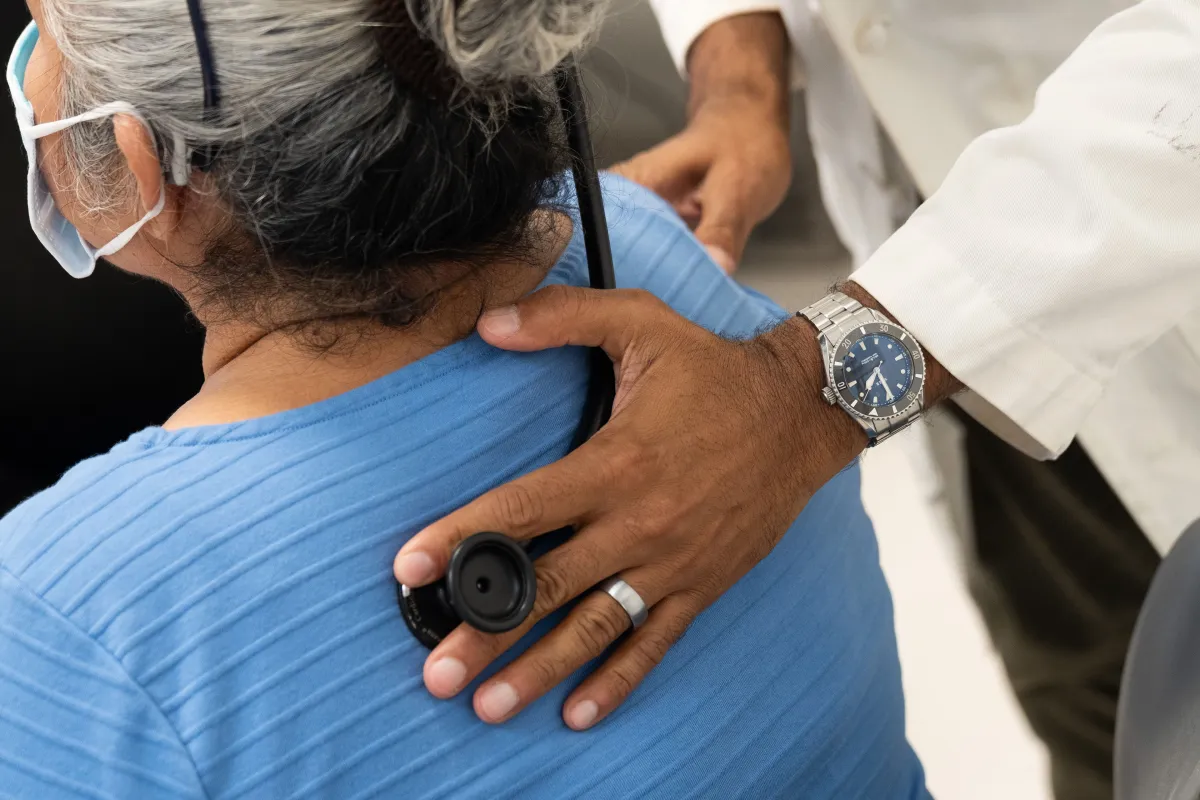 A doctor uses a stethoscope on a patient's back