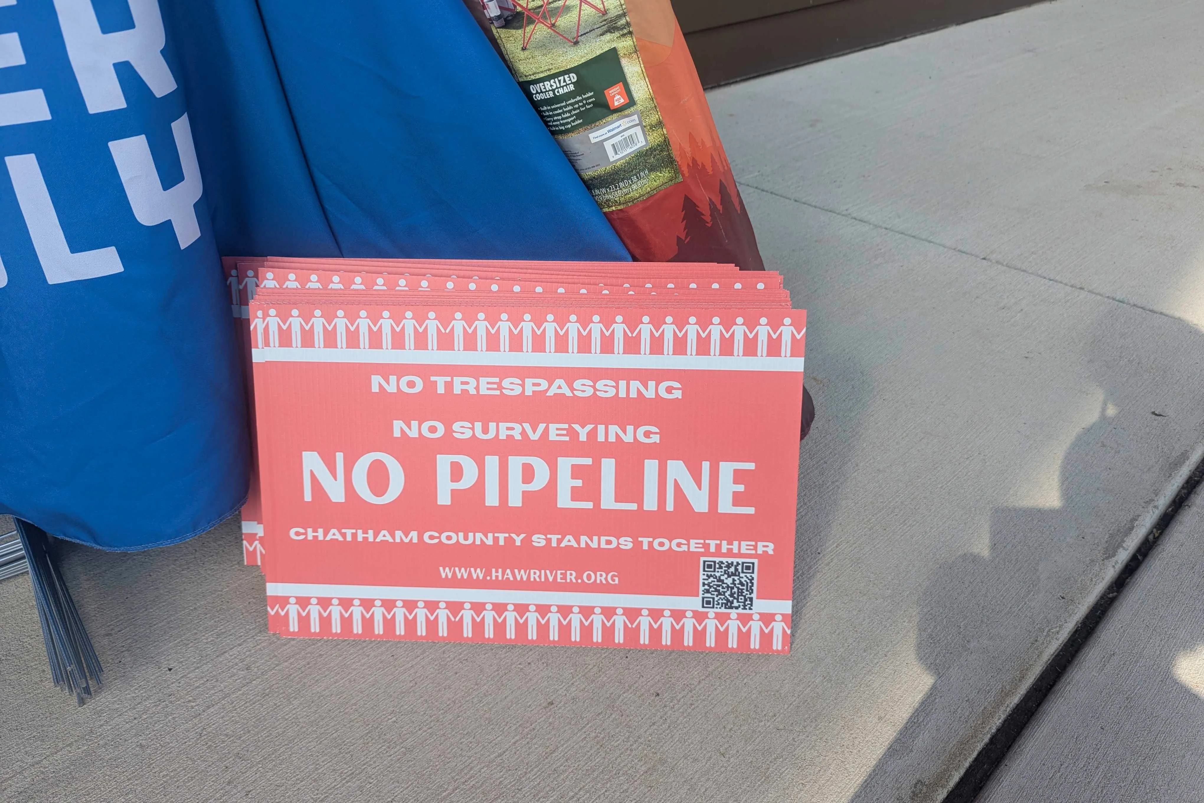 A close-up photo of a stack of red signs that read, "No trespassing. No surveying. No pipeline. Chatham County stands together."
